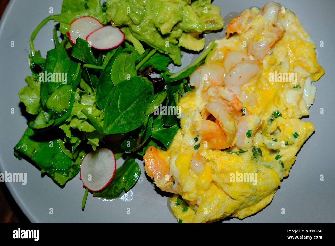 Huevos revueltos con gambas Spanisches weiches Rührei mit Garnelen und Guacamole Stockfoto