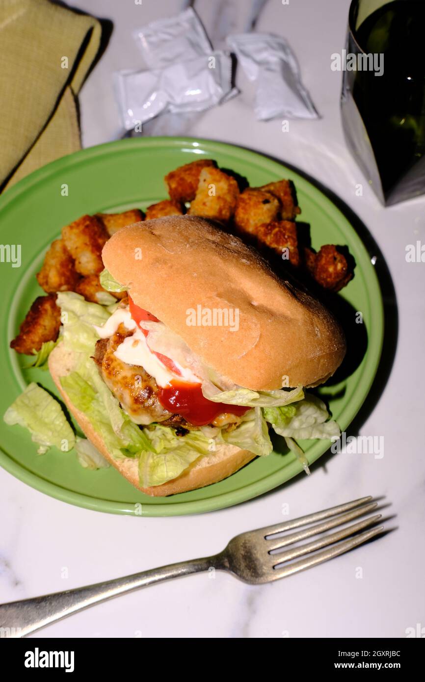 Putenburger auf Ciabatta-Rolle mit Provolonkäse und Tater Tots Stockfoto