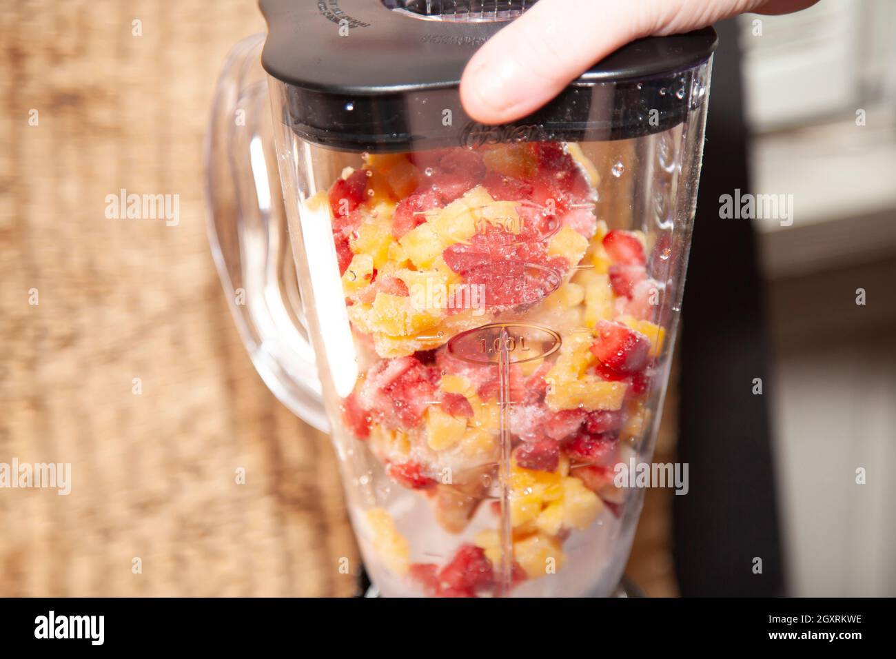 Gewürfelte gefrorene Erdbeeren, Mango und Banane in einem Mixer Stockfoto