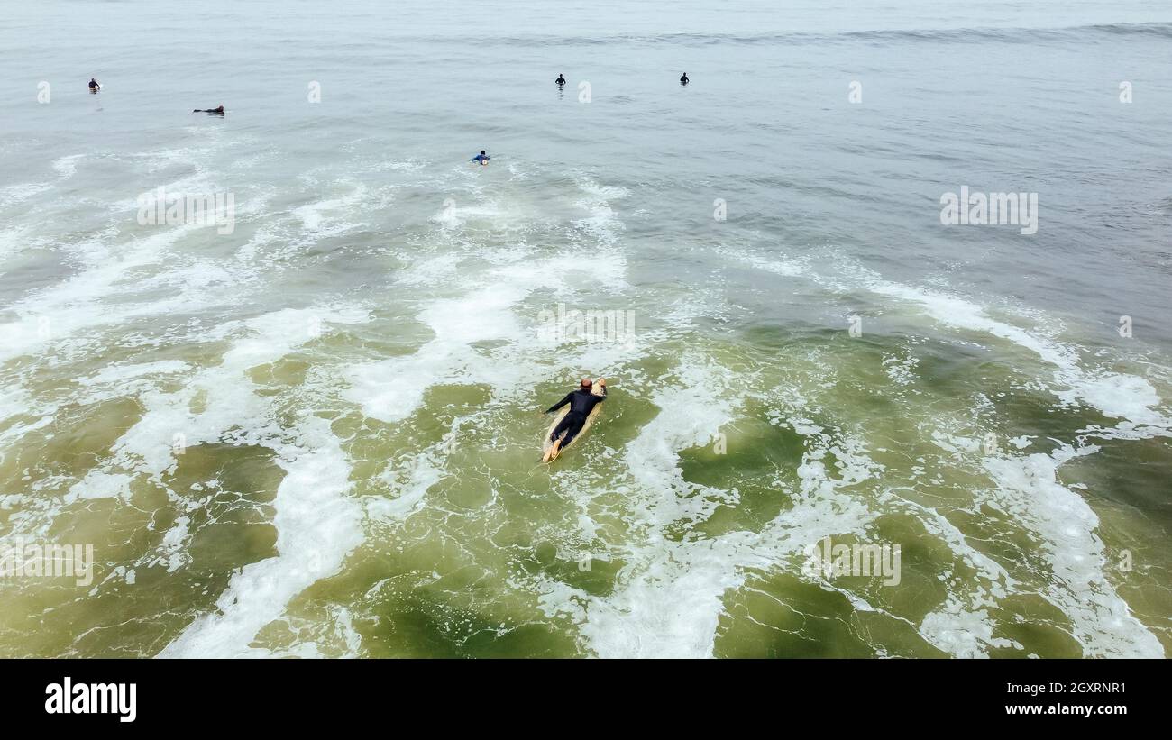 Reifer Mann paddeln, auf einem Surfbrett liegen - sportlicher Senior beim Surfen im Pazifischen Ozean, an einem sonnigen Tag mit blauem Himmel und transparenten Wellen Stockfoto