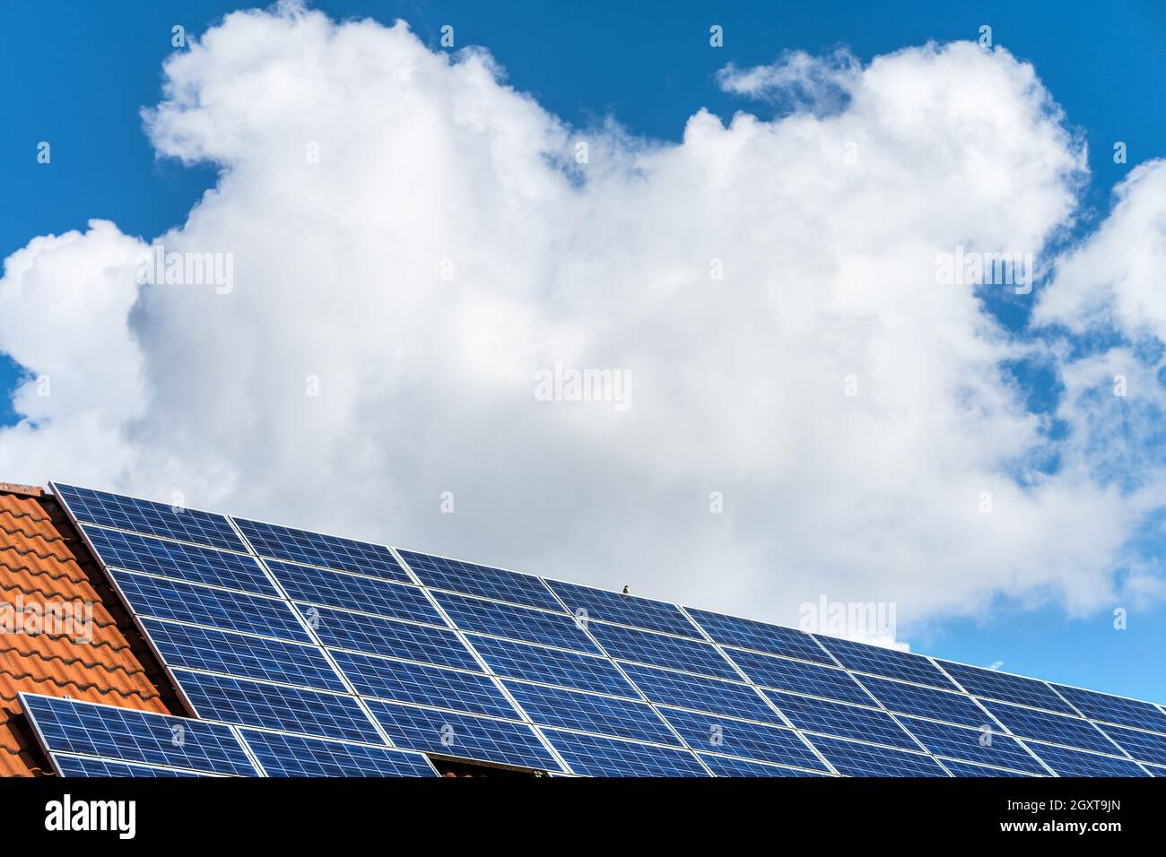 Sonnenkollektoren und Solaranlage Photovoltaik auf dem Dach eines Privathauses und dem weiß-blauen bayerischen Himmel Stockfoto