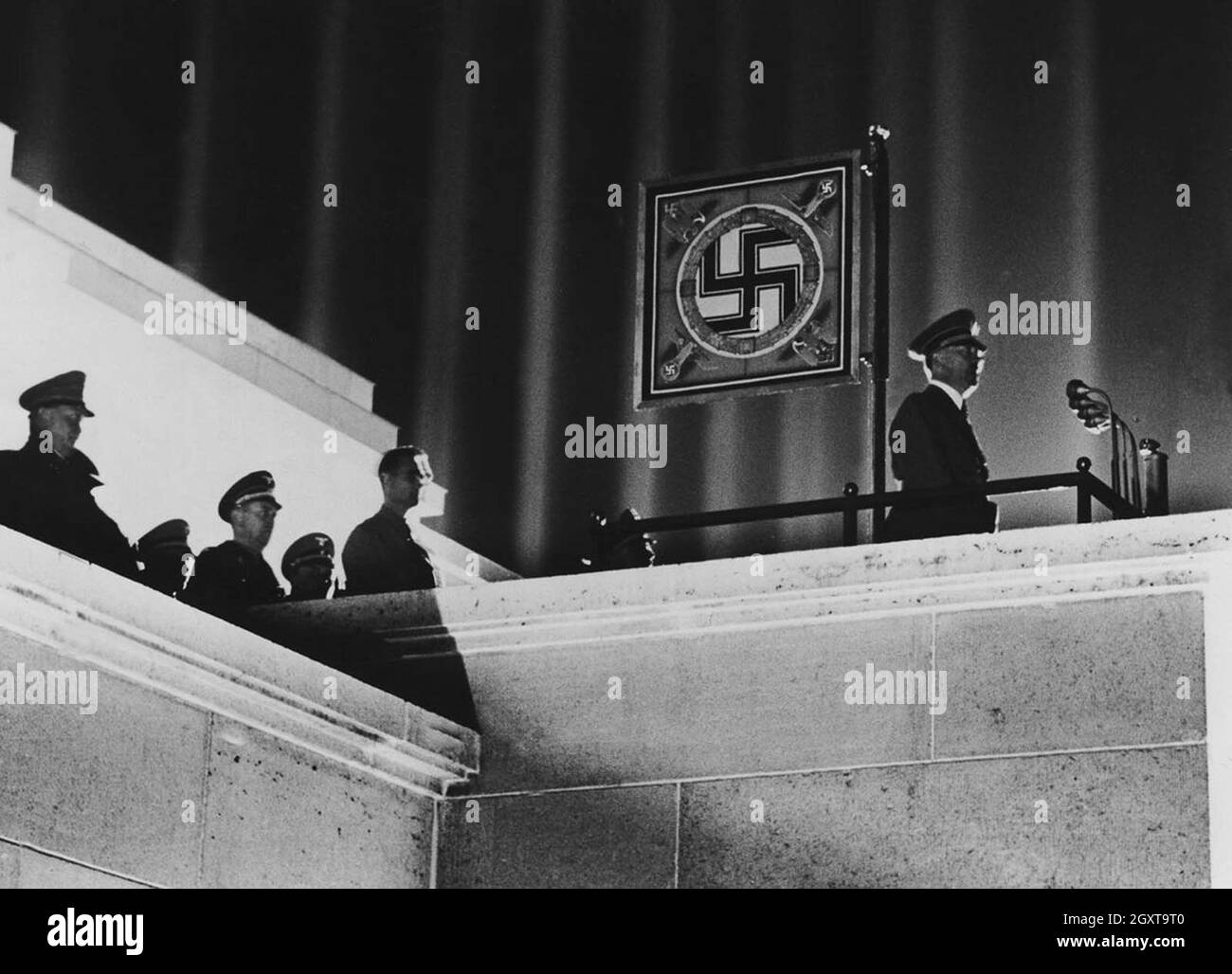 Hitler und ein Hakenkreuz-Standard mit der beeindruckenden Lichtkathedrale, entworfen von Albert Speer, bei der NSDAP-Kundgebung in Nürnberg Stockfoto