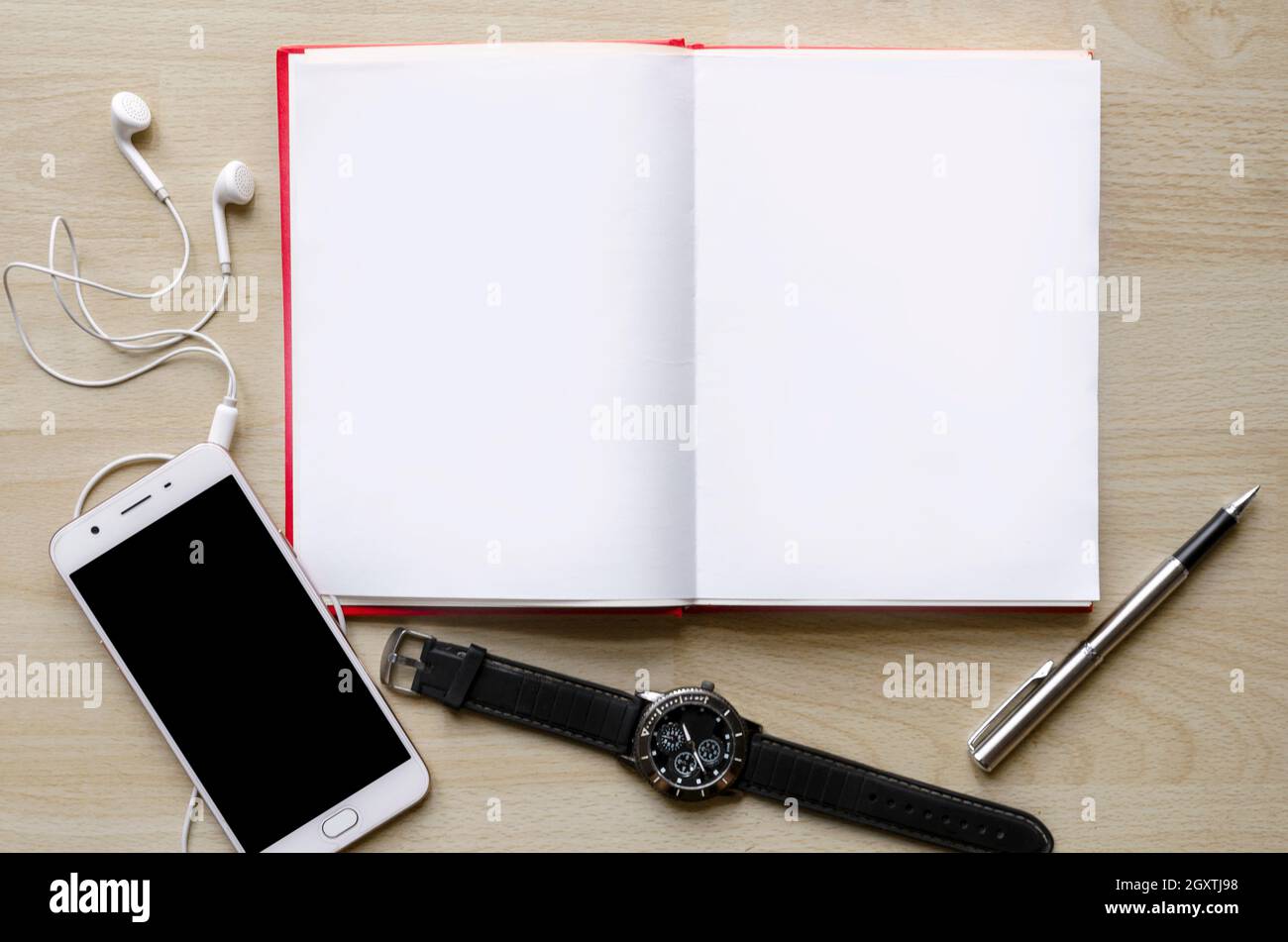 Leeres Notizbuch mit Stift auf Holztisch und einem Handgelenk-Uhr-Headset modernes Telefon Texteingabebereich Stockfoto