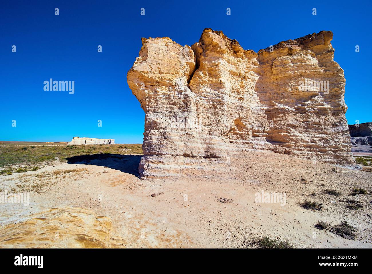 Riesige Säule aus weißem und goldbraunem Felsen in Wüstenlandschaft gegen blauen Himmel Stockfoto