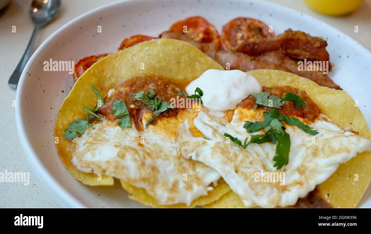 Frühstück Hard Shell Tacos und Bacon Tomaten und Eier am Morgen Mahlzeit auf einem Teller Stockfoto