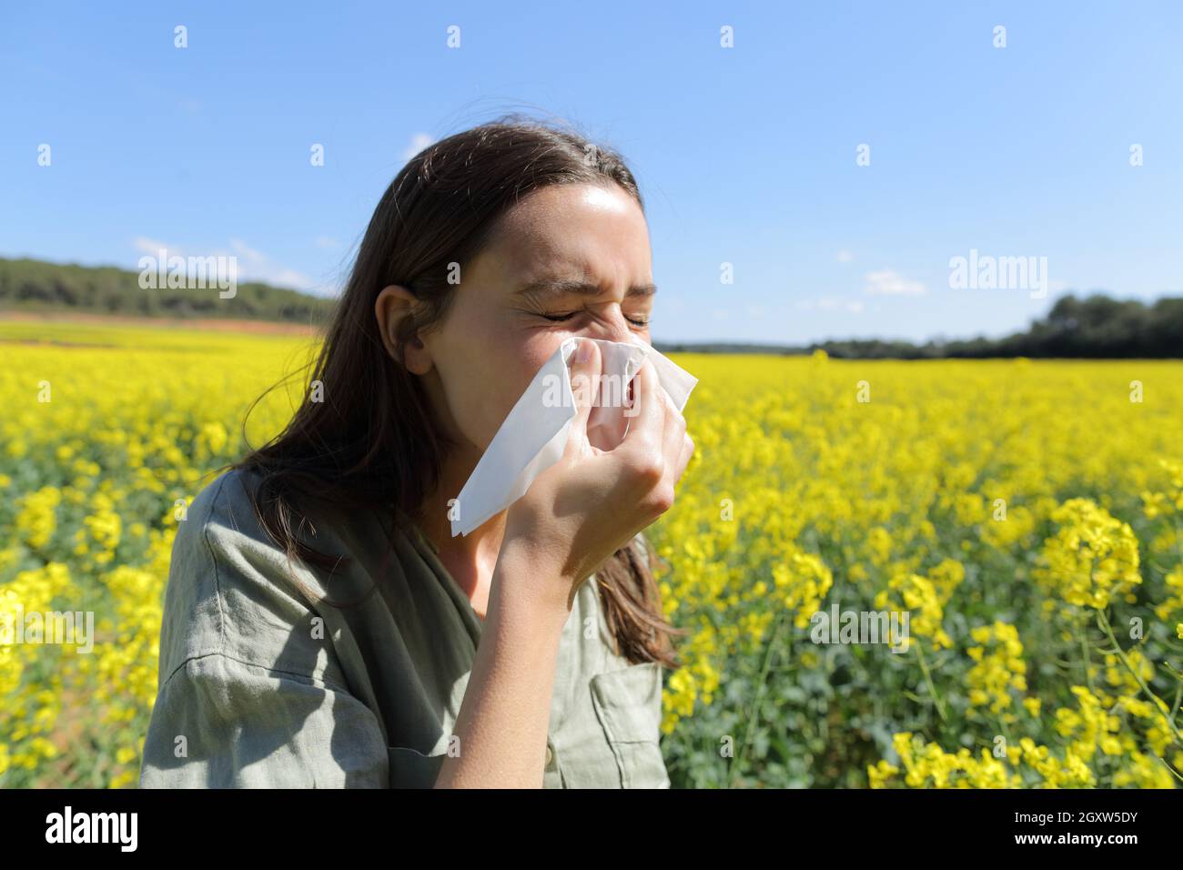 Allergische Frau, die im Frühling auf einem Feld steht und Nase bläst Saison Stockfoto