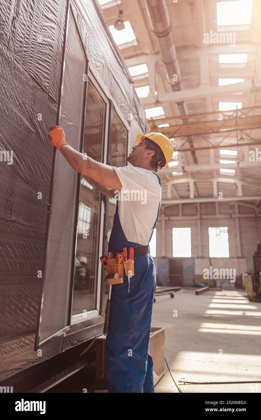 Männlicher Baumeister installiert Glasschiebetür an der Einengung Stockfoto