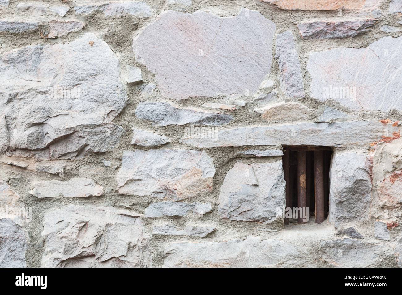 Alte Steinmauer mit kleinen eisernen Gefängniszelle Fenster gesperrt. Stockfoto