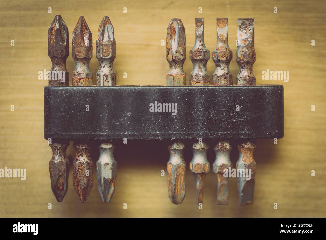 Nahaufnahme einiger rostiger Schraubendreherköpfe und -Bits auf einem Holzhintergrund. Stockfoto