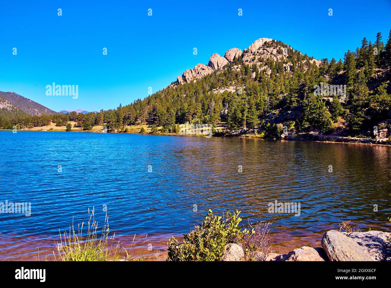 Blauer See mit felsigen Bergen im Hintergrund und strahlend blauem Himmel Stockfoto