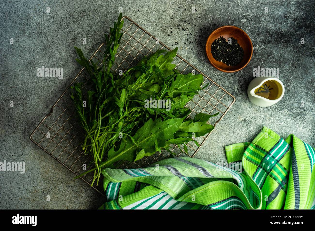 Frische Bio-Rucola-Blätter auf einem Kühlgestell mit Olivenöl und schwarzen Sesamsamen Stockfoto