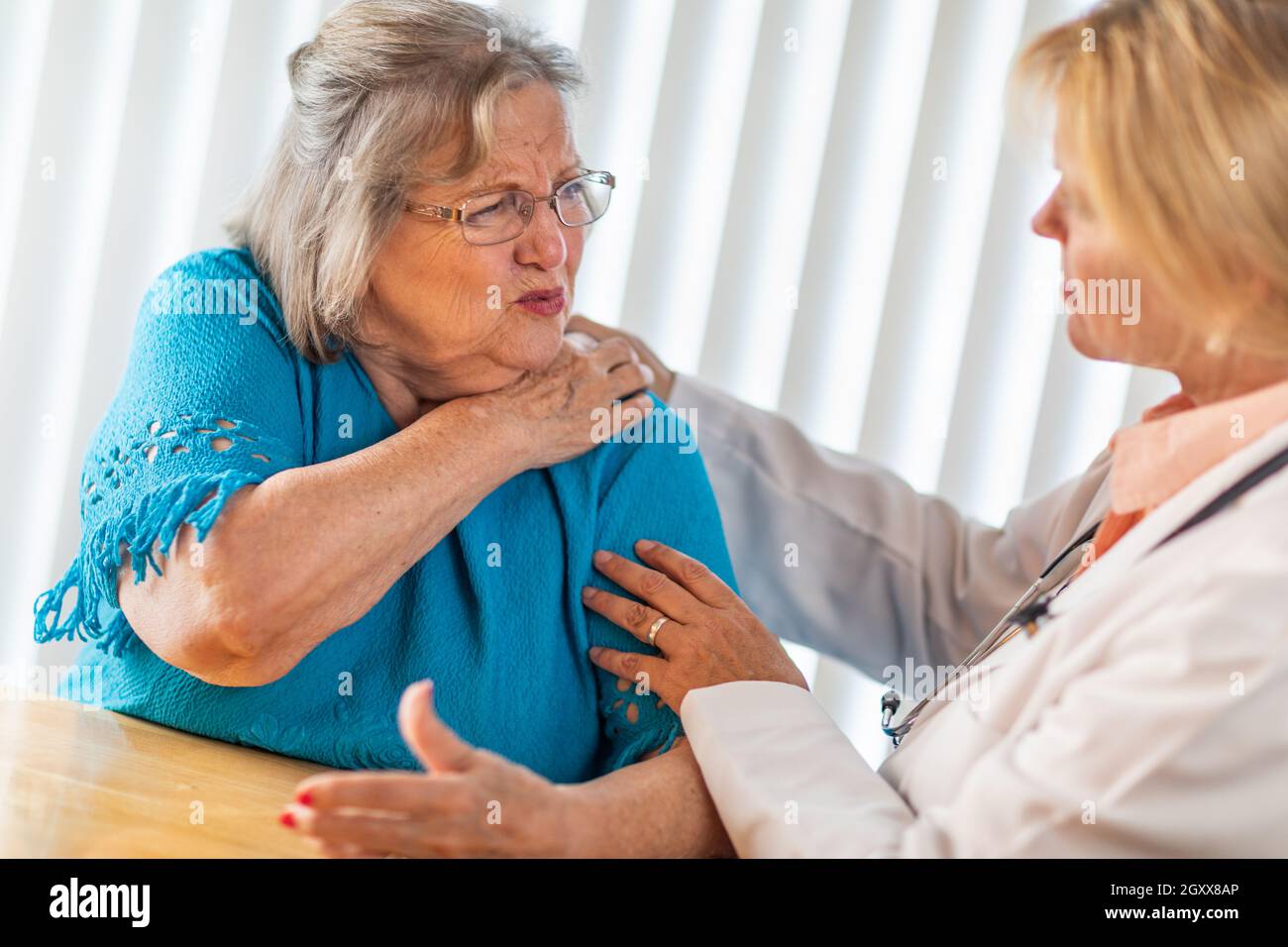 Ältere Erwachsene Frau im Gespräch mit Frau Doktor über schmerzende Schulter. Stockfoto