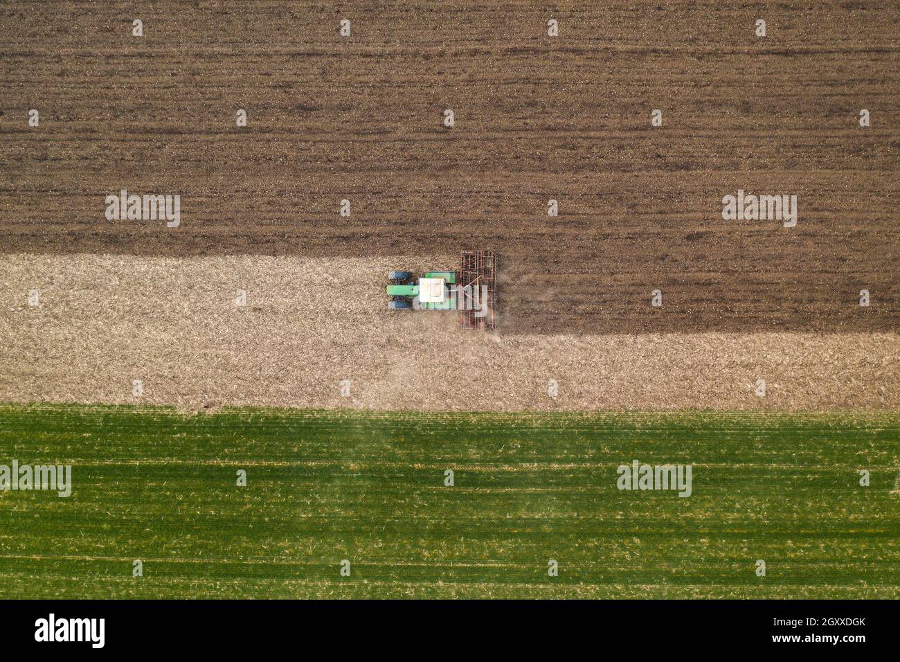 Luftaufnahme der landwirtschaftlichen Traktor Bodenbearbeitung und erschütternde gepflügten Feld, direkt über Drohne pov Bild von Maschinen arbeiten auf Ackerland Stockfoto