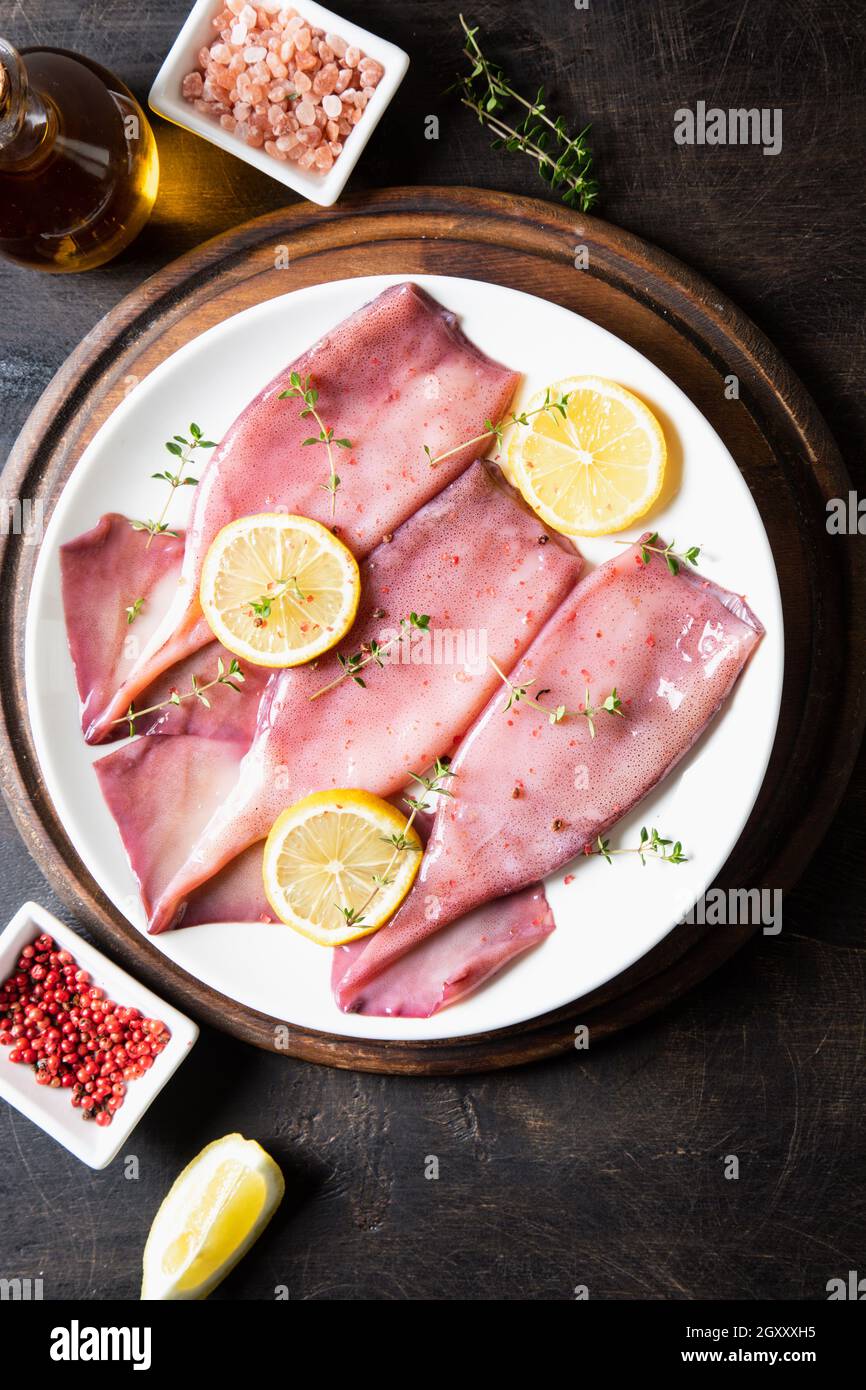 Frische Tintenfische oder Tintenfische für gekochte Speisen. Frischer roher Tintenfisch. Roher Tintenfisch mit Zitrone. Draufsicht und Kopierbereich für Ihren Text Stockfoto