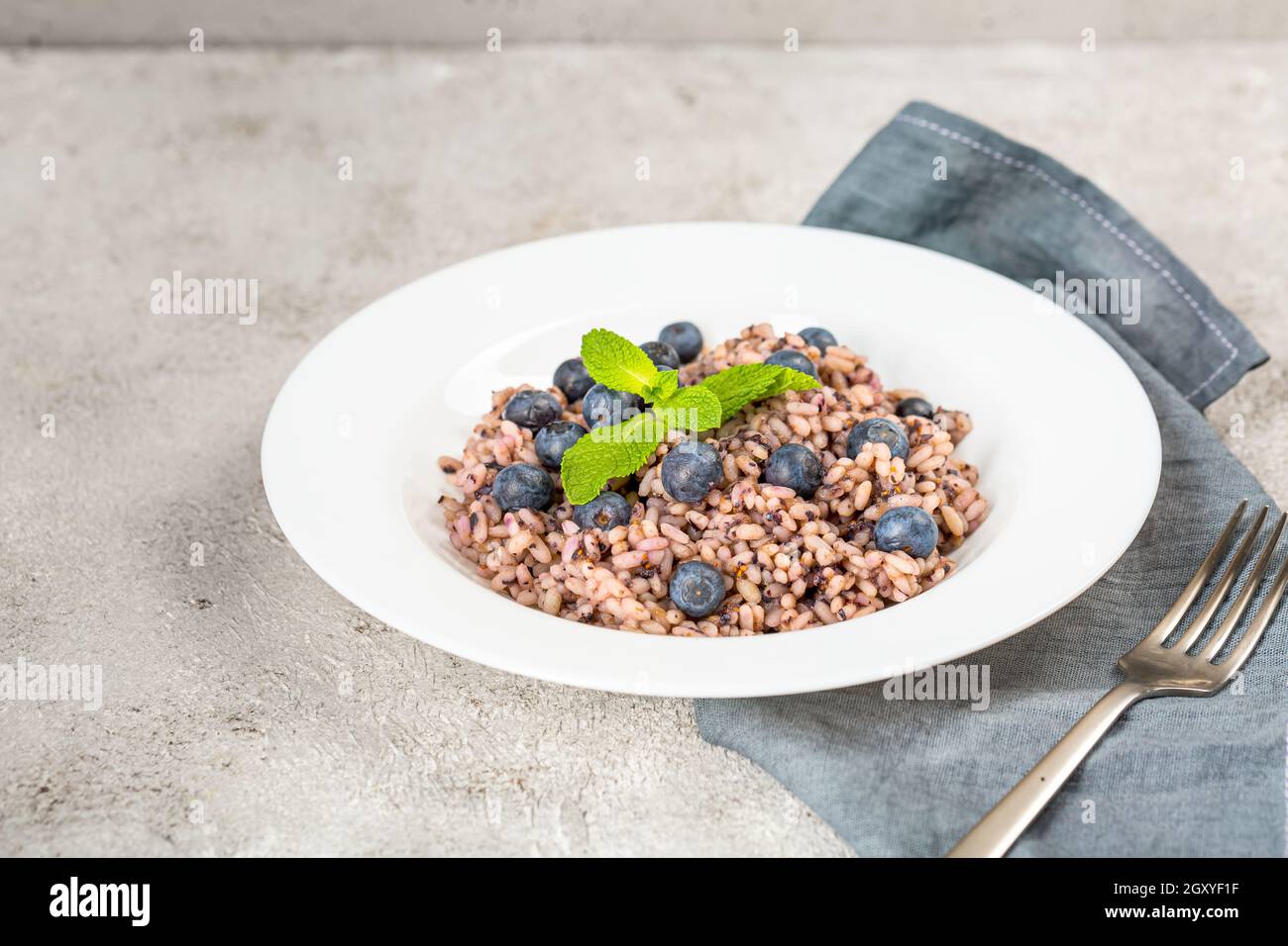 Frische und gesunde vegane Reisschüssel mit Heidelbeerfrüchten serviert. Diät-Konzept. Platz für Ersatzfarben kopieren. Bild für Ihren Food-Blog auf Social Stockfoto