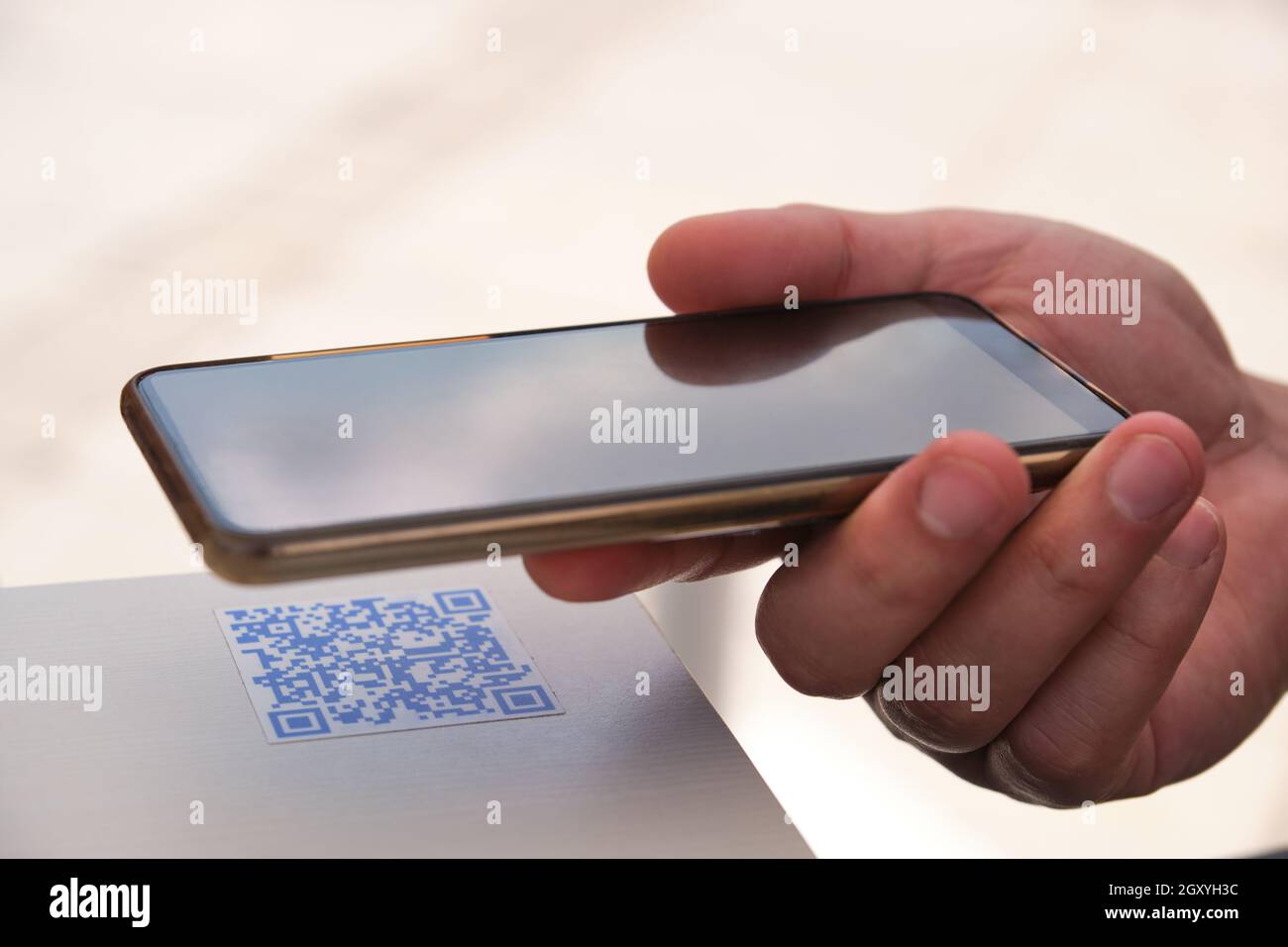 Mann Hand mit dem Smartphone, um den QR-Code in einem Bartisch scannen. Stockfoto