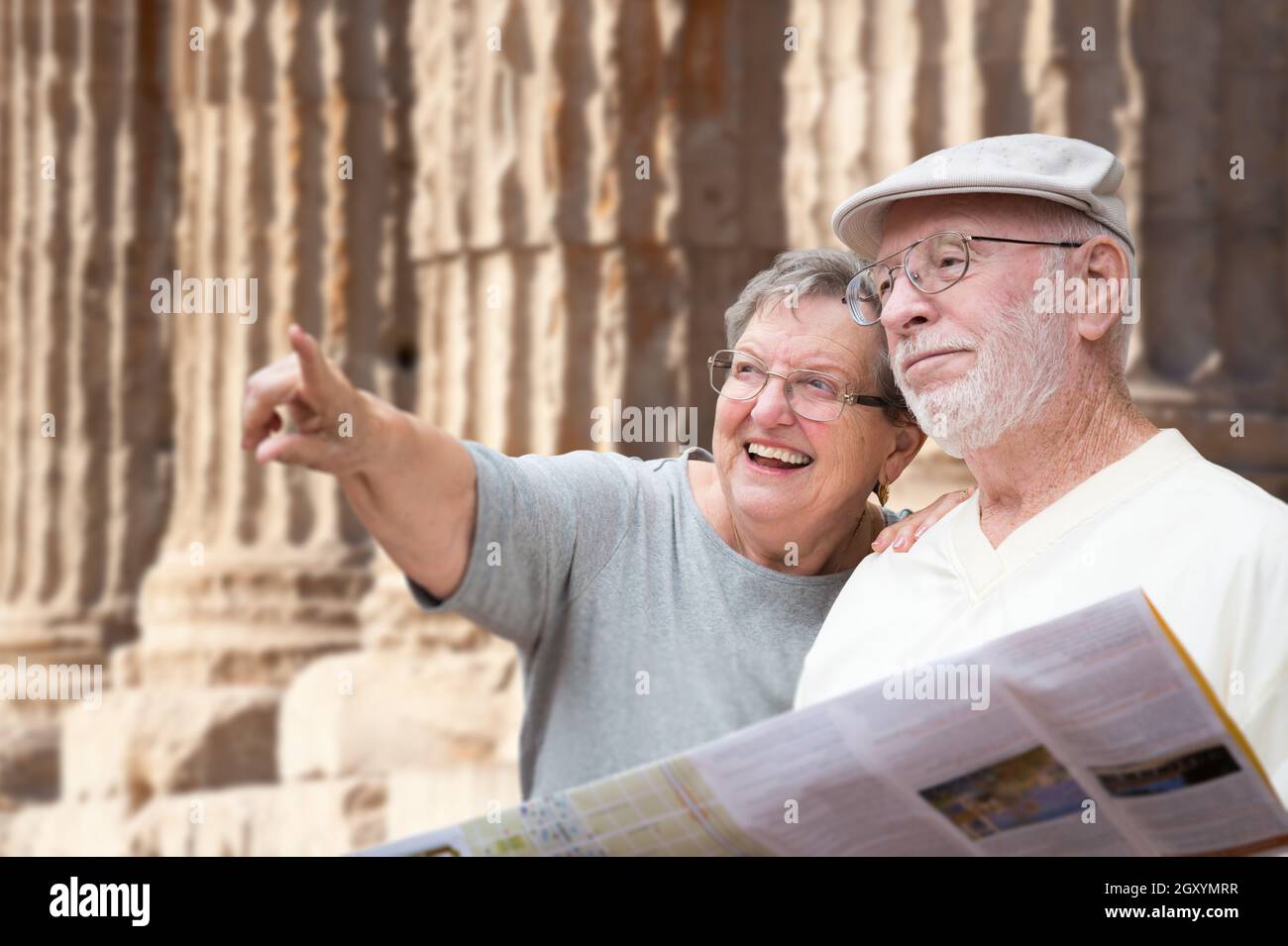 Gerne älterer Erwachsener Paar Touristen mit Broschüre Neben alten Spalte Ruinen. Stockfoto