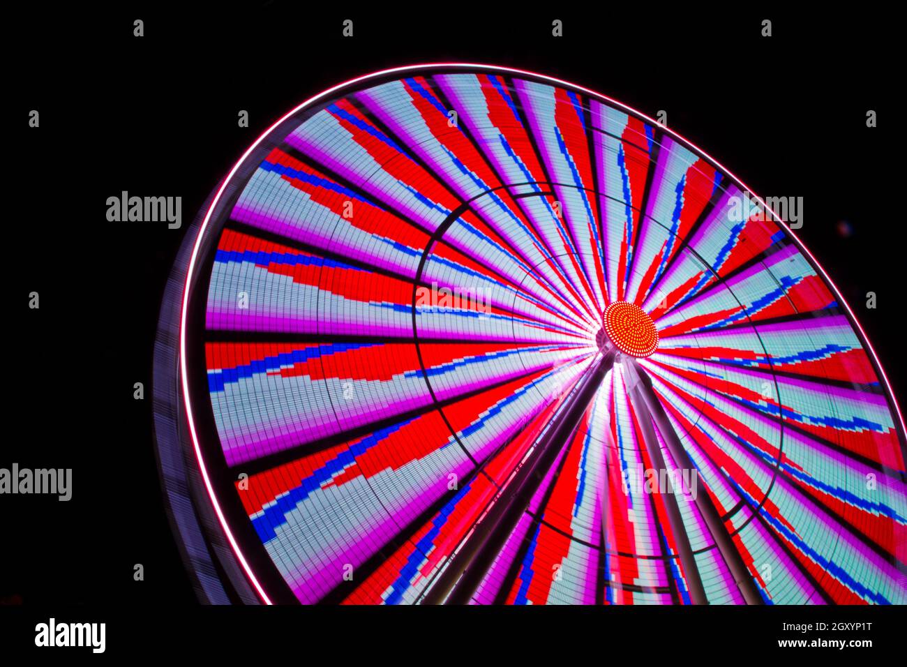 Das Riesenrad ist nachts mit roten Blautönen und violett beleuchtet Stockfoto