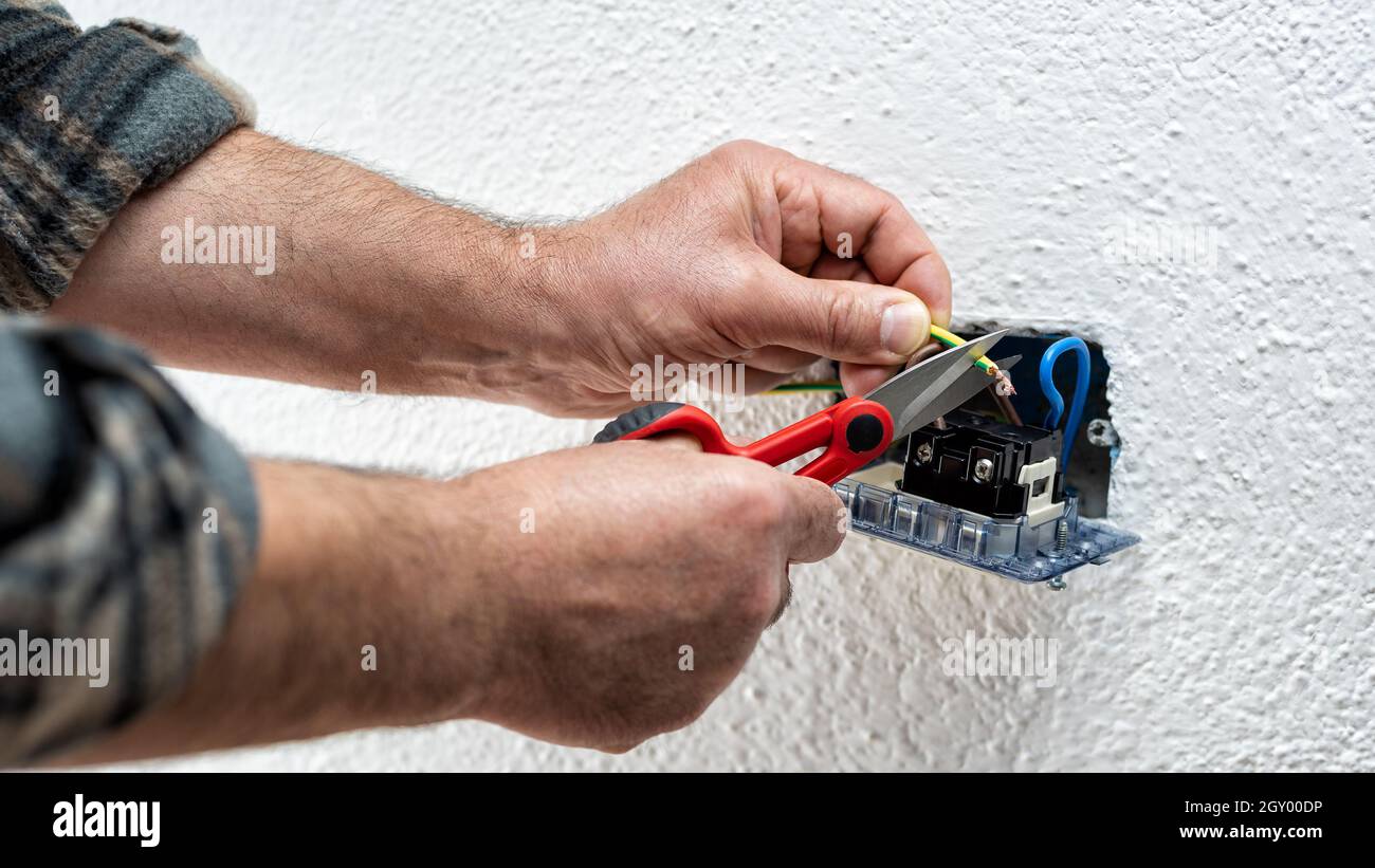 Elektriker bei der Arbeit mit einer Schere bereitet die elektrischen Kabel eines elektrischen Systems vor. Bauindustrie. Stockfoto