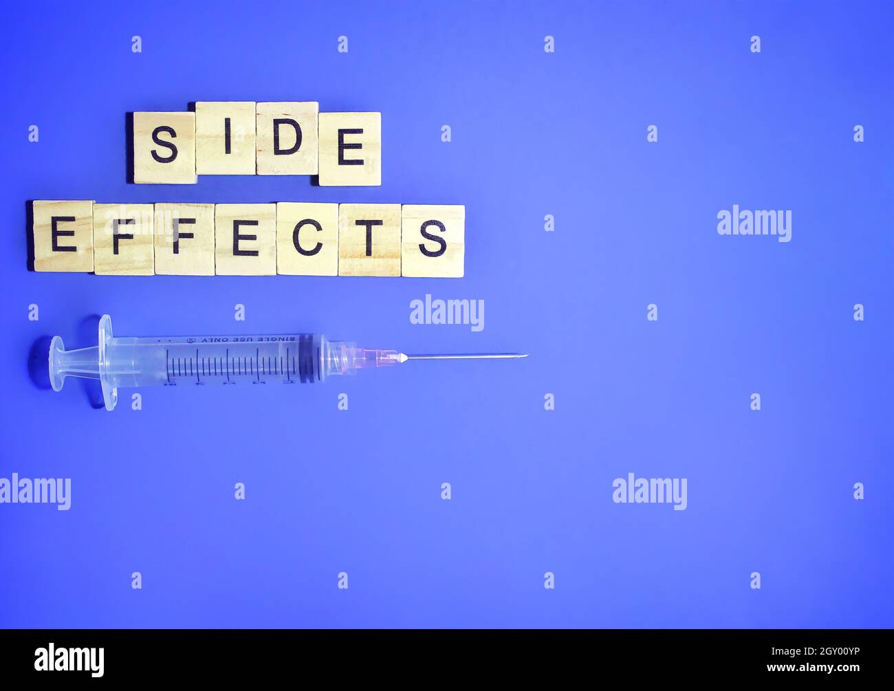 Draufsicht auf medizinische Spritze und Holzwürfel mit Text-NEBENWIRKUNGEN auf blauem Hintergrund. Platz für Text kopieren Stockfoto