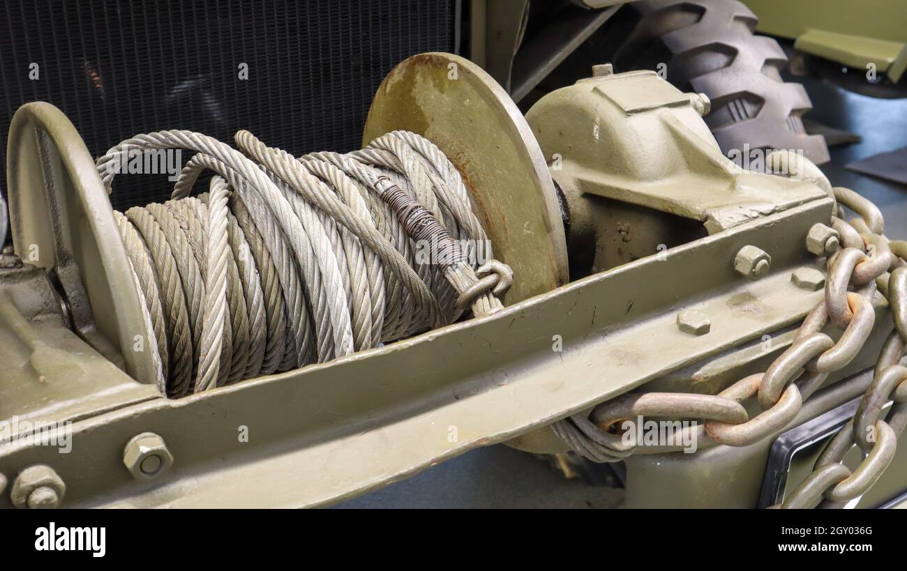 Ein detailliertes Foto einer mechanischen Winde mit einem Kabel. Ein rostig altes Abschleppseil, das an einem schweren Militärfahrzeug befestigt ist Stockfoto