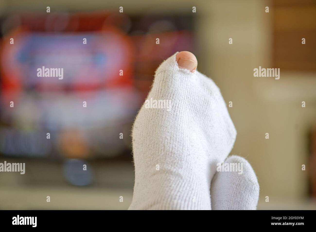 Große Zehe, die aus einem Loch in der Socke guckt Stockfoto