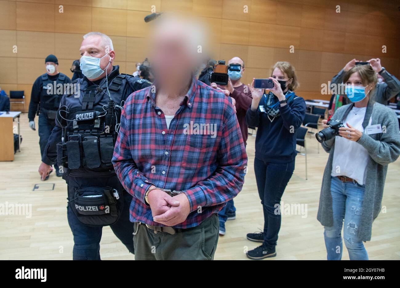 Hanau, Deutschland. Oktober 2021. Der Angeklagte wird von einem Polizisten in den Gerichtssaal geführt. Der Mann ist der Vater des Attentäters von Hanau, der 2019 aus rassistischen Motiven neun Menschen mit Migrationshintergrund ermordet hatte, bevor er vermutlich seine Mutter und schließlich sich selbst tötete. Der Mann steht nun mehreren Beleidigungen gegenüber. Kredit: Boris Roessler/dpa - ACHTUNG: Person(en) wurden aus rechtlichen Gründen/dpa/Alamy Live News pixeliert Stockfoto