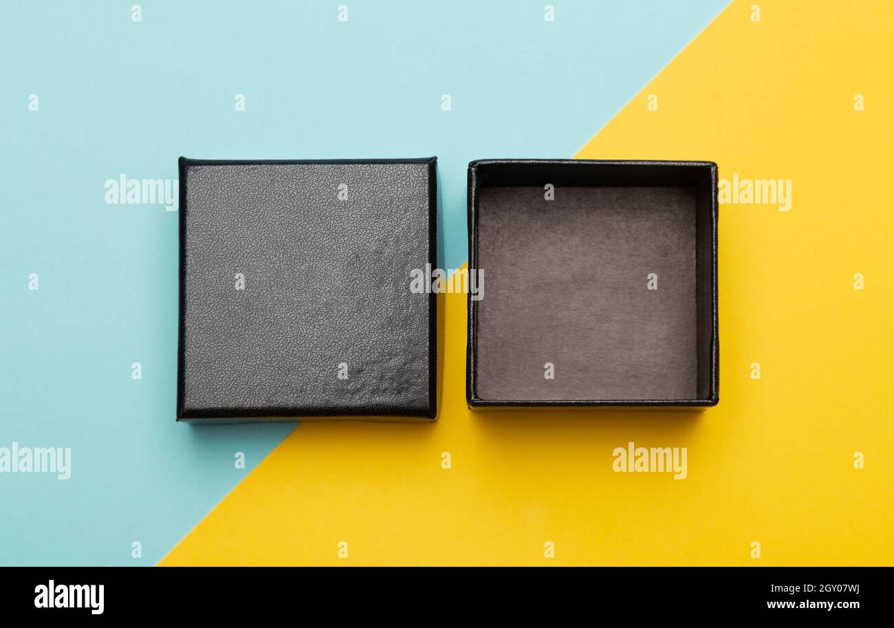 Mini Black Box Produktverpackung isoliert auf gelben halben blauen Hintergrund. Flach liegend Ansicht von oben. Stockfoto