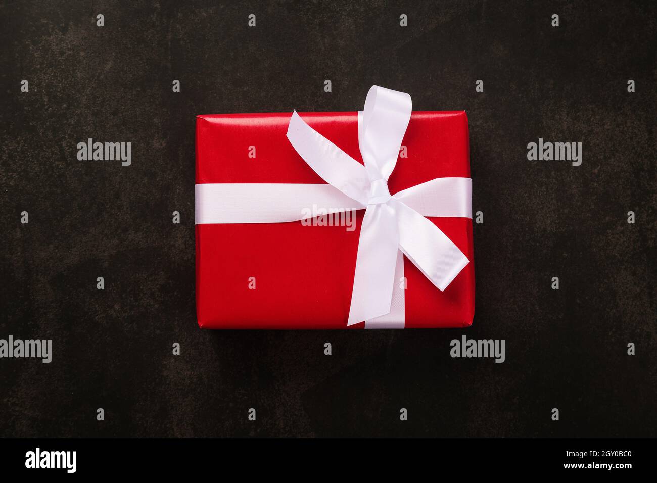 Draufsicht auf Weihnachten Geschenkbox mit rotem Papier und weißem Band auf grunge Hintergrund verpackt. Stockfoto