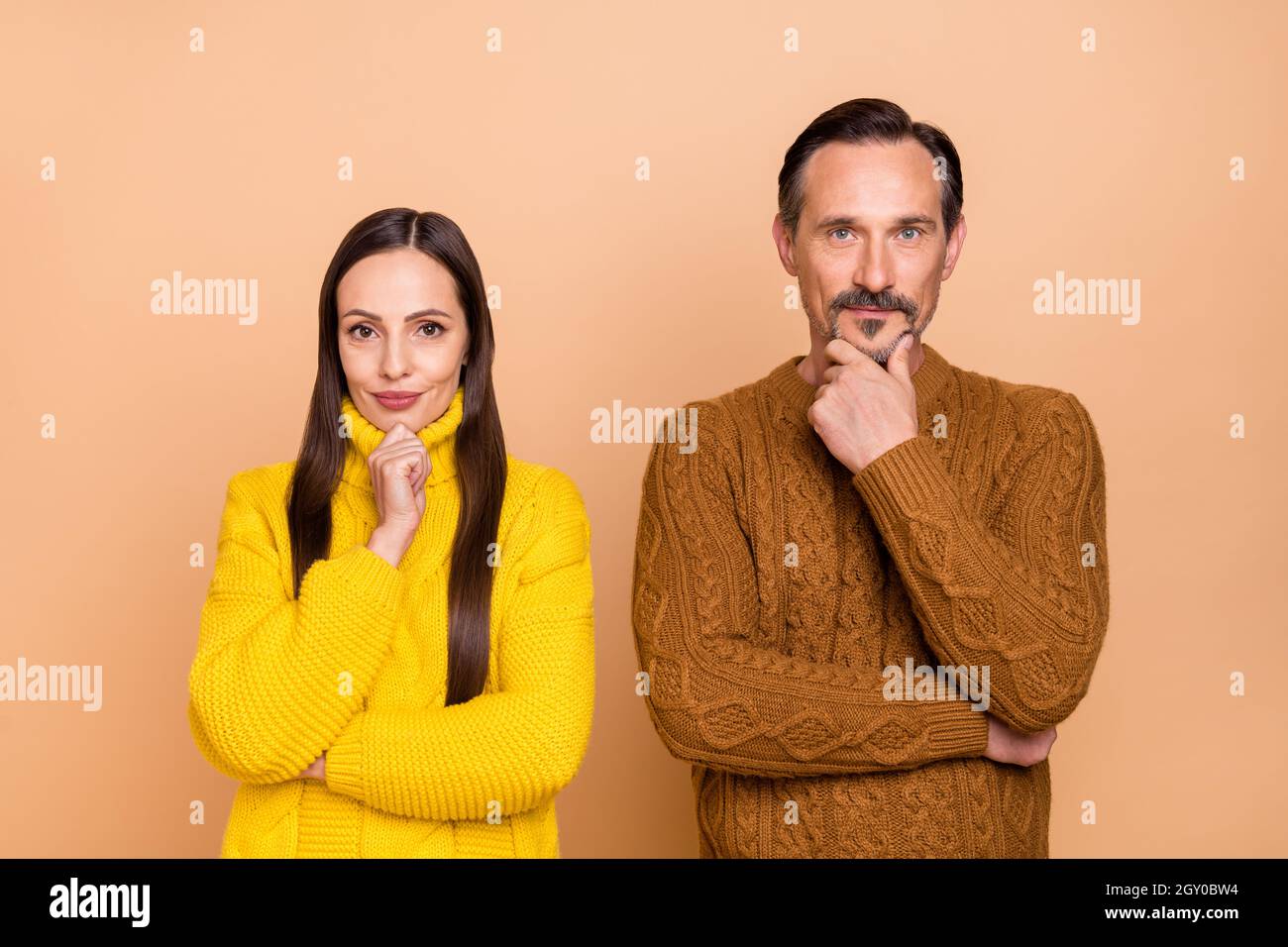 Foto von Think Brunette Paar Hand Gesicht tragen fallen Strickmode Pullover isoliert auf beige Farbe Hintergrund Stockfoto