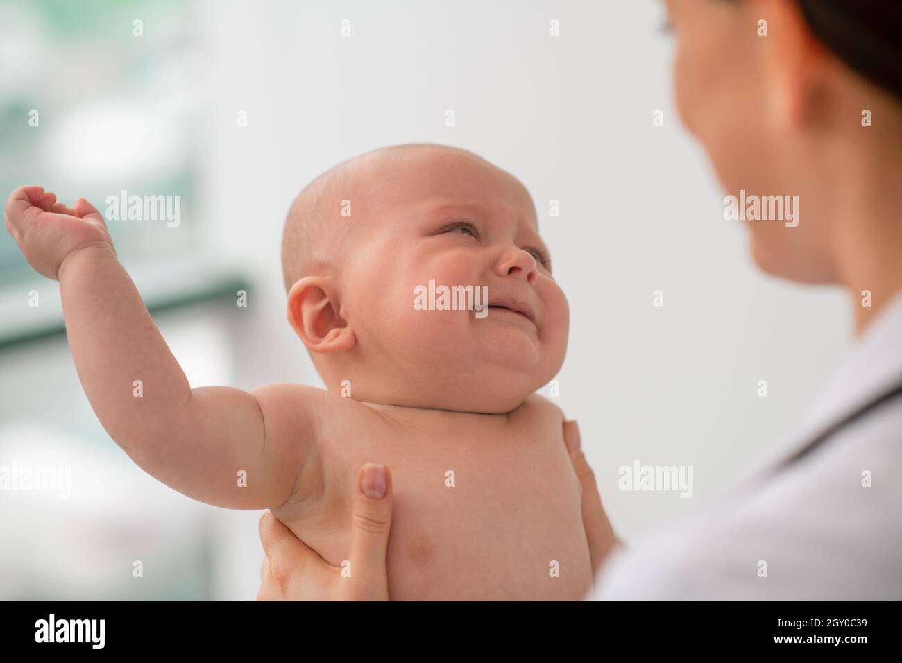 Trauriges Baby, das während der körperlichen Untersuchung einen Kinderarzt ansieht Stockfoto