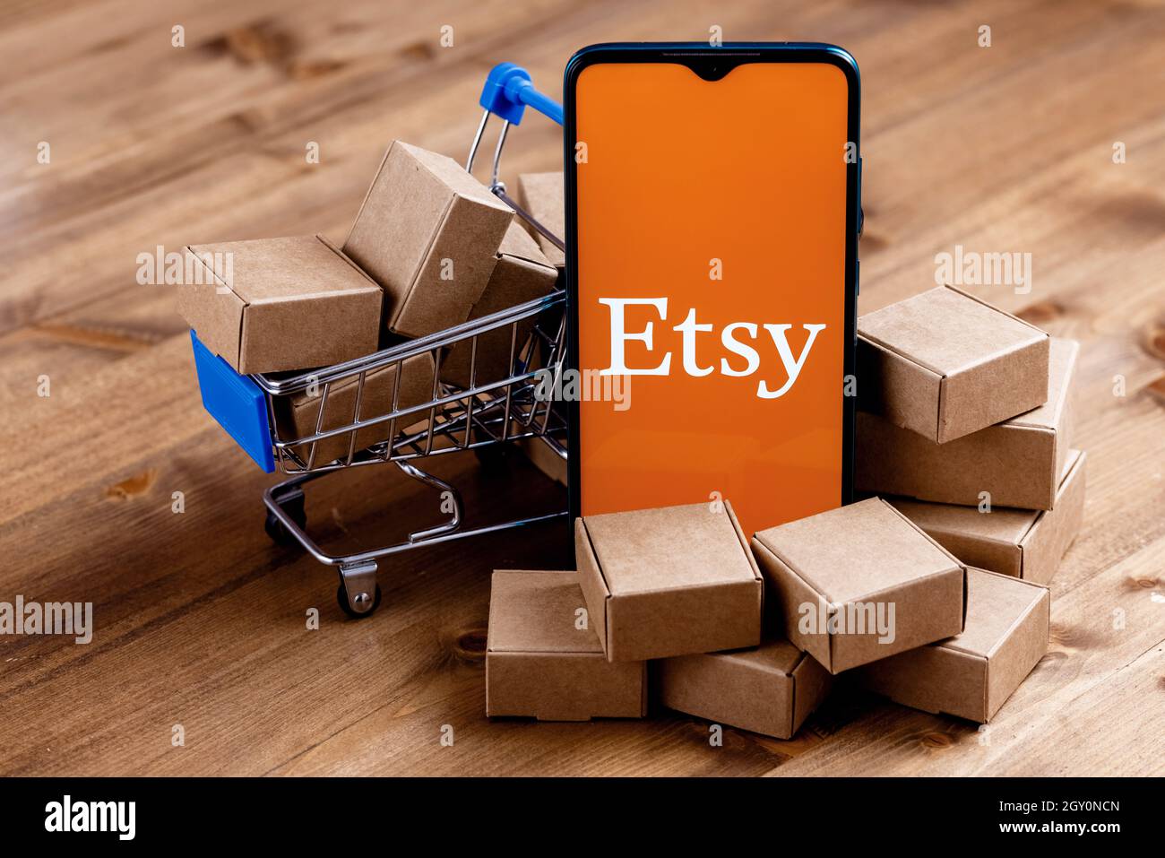 Smartphone mit Etsy-Logo auf dem Bildschirm, Warenkorb und Paketen. Stockfoto