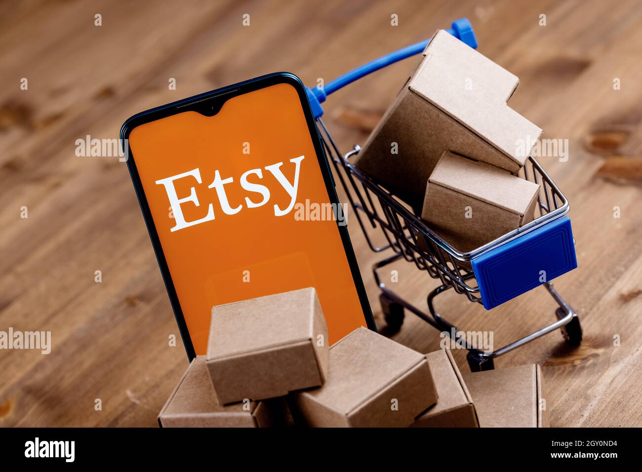 Smartphone mit Etsy-Logo auf dem Bildschirm, Warenkorb und Paketen. Stockfoto
