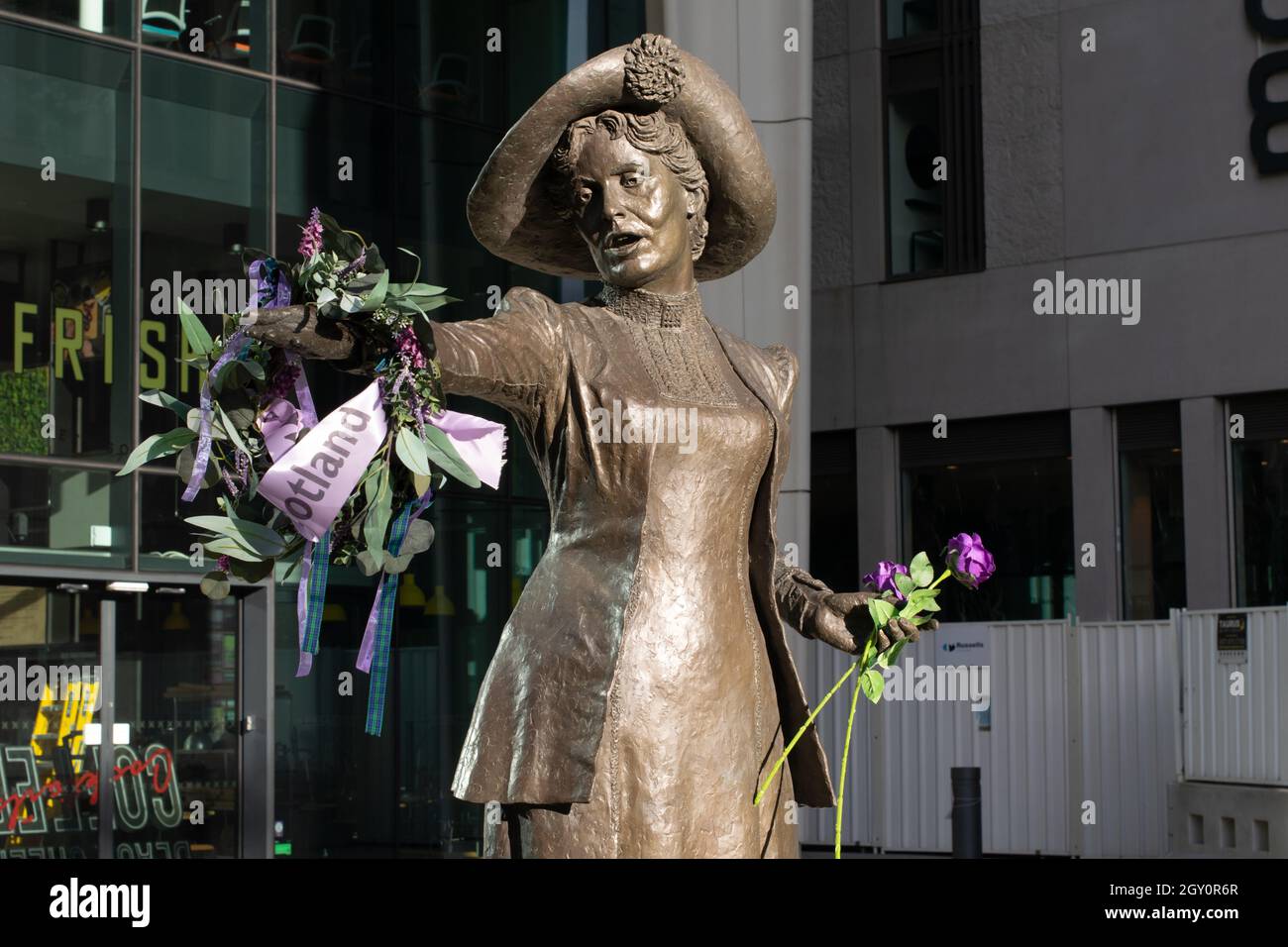 Emmeline Pankhurst Statue, Manchester UK, mit schottischem Kranz auf einer Hand. Schartanfarbene und violette Farbtöne. Petersplatz Stockfoto