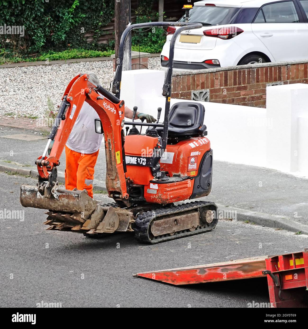 Anlage mieten Unternehmen Lieferung LKW-Fahrer sammeln Mini Bagger Bagger Maschine Lenk-und Wandermaschine auf der Straße auf LKW-Rampe England Großbritannien Stockfoto