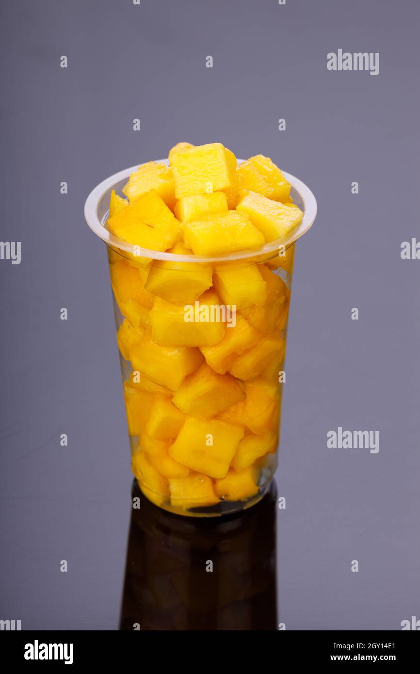 Reife Mango Würfel oder geschnittenes Stück in einem transparenten Glas mit schwarzem Hintergrund angeordnet. Stockfoto