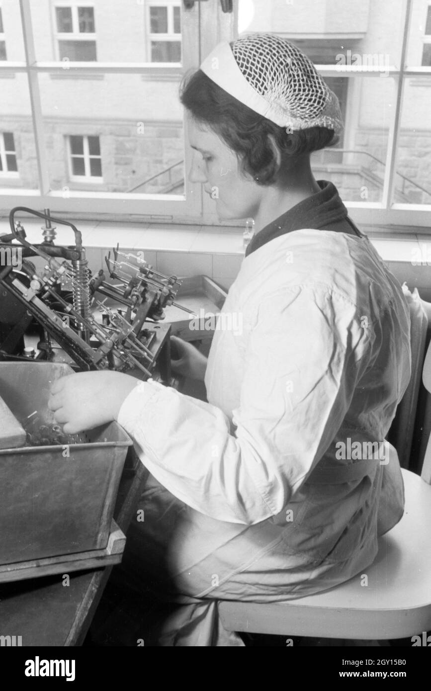 Eine Laborantin fertigt in Arbeit der Behringwerke mithilfe einer technischen Apparatur Proben eines Medikaments ein, Marburg, Deutschland 1930er Jahre. Eine Lab Assistant ist die Einnahme von Medikamenten Proben mit Hilfe der ein technisches Instrument im Labor der Behringwerke, Marburg, Deutschland 1930. Stockfoto