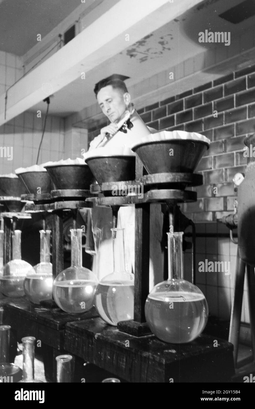 Ein Laborant füllt Medikamentenproben in große Glaskolben in Arbeit der Behringwerke ab, Marburg, Deutschland 1930er Jahre. Eine Lab Assistant ist die Abfüllung Medizin Proben in grossen Glaskolben in einem Labor der Behringwerke, Marburg, Deutschland 1930. Stockfoto