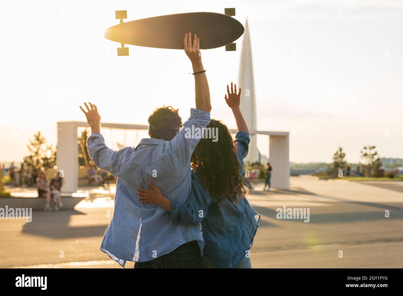 Stilvolle junge Paar Umarmung Blick auf Sonnenuntergang halten Skateboard. Glückliches Mädchen und Kerl in der Liebe genießen Freiheit Stockfoto