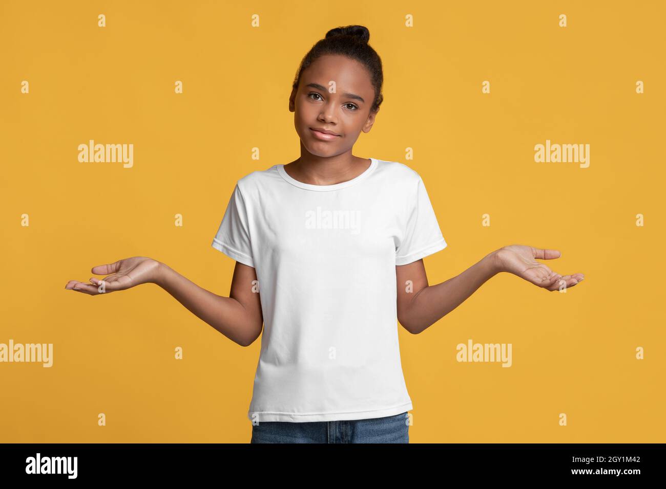 Verwirrt Teenager afroamerikanische Mädchen in weißem T-Shirt macht Wahl, spreizte ihre Arme zu den Seiten Stockfoto