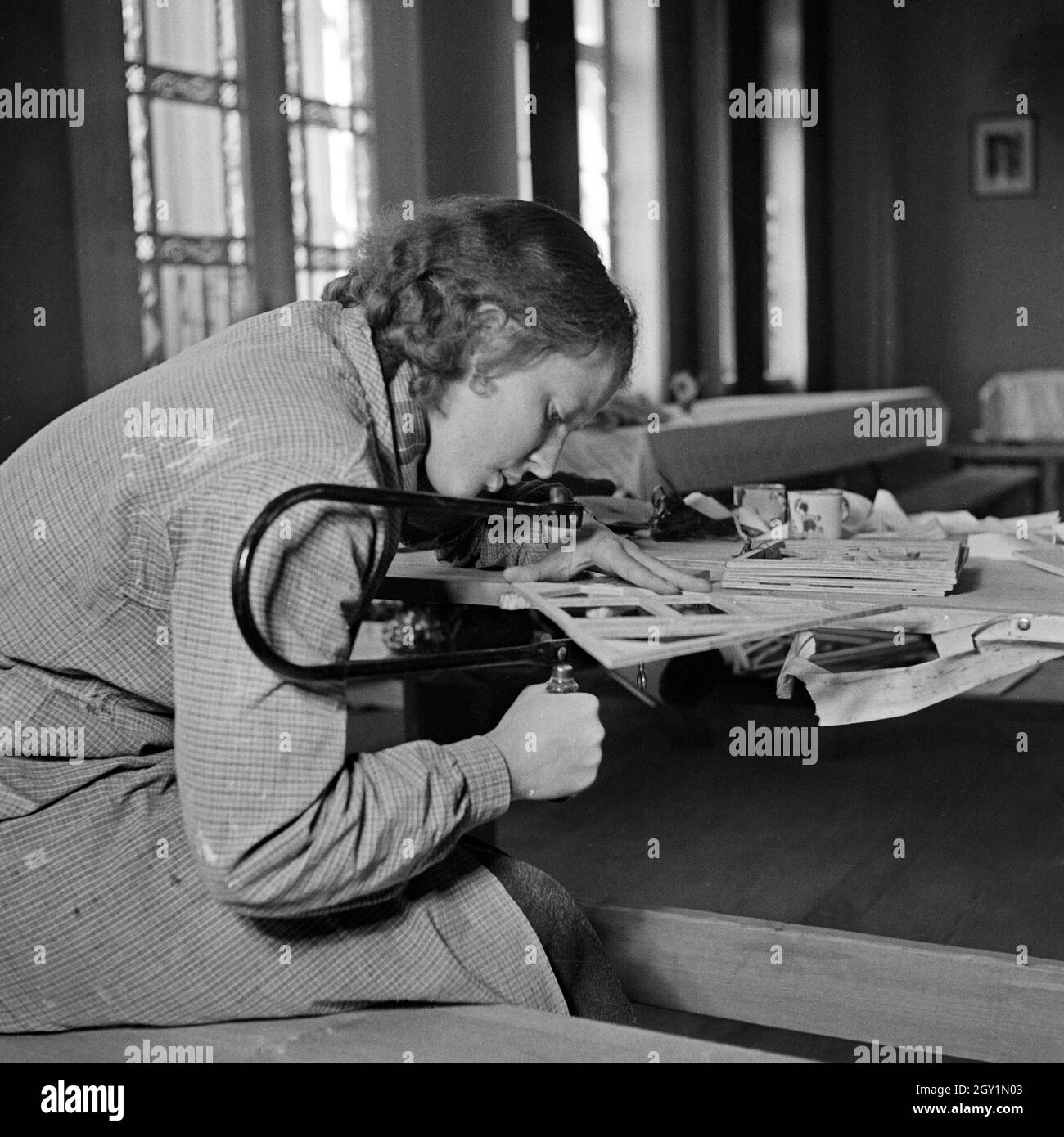 Eine Frau bei Laubsägearbeiten beim weiblichen Arbeitsdienst in Molkenberg bei Fürstenwalde, Deutschland 1930er Jahre. Eine Frau dabei einige eckappliken an der weiblichen Belegschaft Gruppe von Molkenberg, Deutschland 1930. Stockfoto