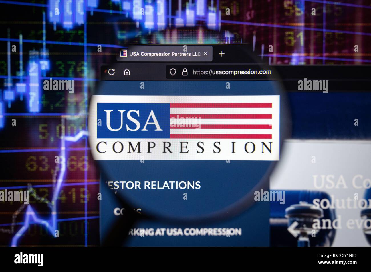 USA Compression Company Logo auf einer Website mit verschwommenen Börsenentwicklungen im Hintergrund, auf einem Computerbildschirm gesehen Stockfoto
