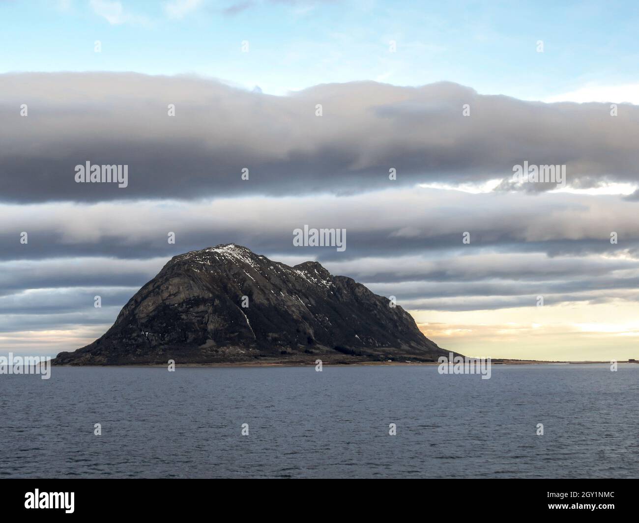 Wolke Linien über einem großen Felsen im arktischen Ozean Stockfoto
