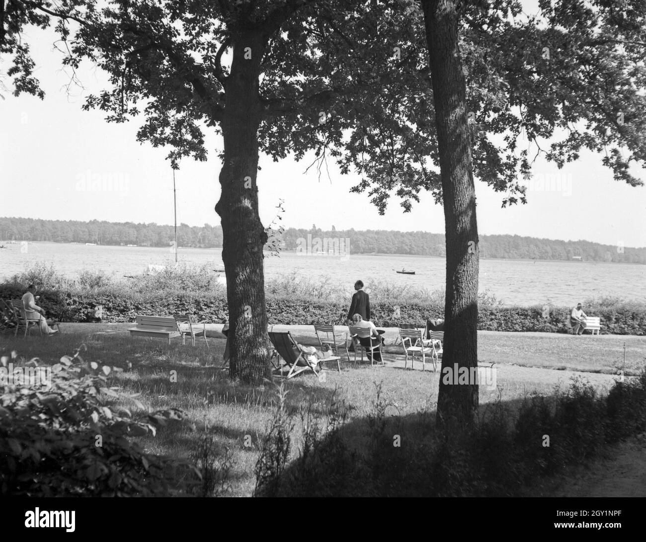 Menschen erholen sich an der Uferpromenade des Sieht, Deutschland 1930er Jahre. Menschen entspannen im Schatten an einem See, Deutschland 1930. Stockfoto
