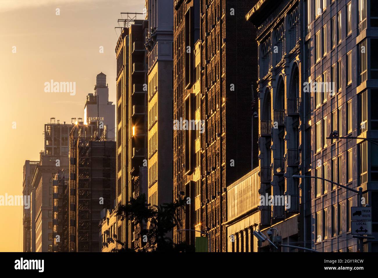 Block historischer Gebäude in New York City mit dem farbenfrohen warmen Licht des Sonnenuntergangs, der lange Schatten über die Fenster wirft Stockfoto
