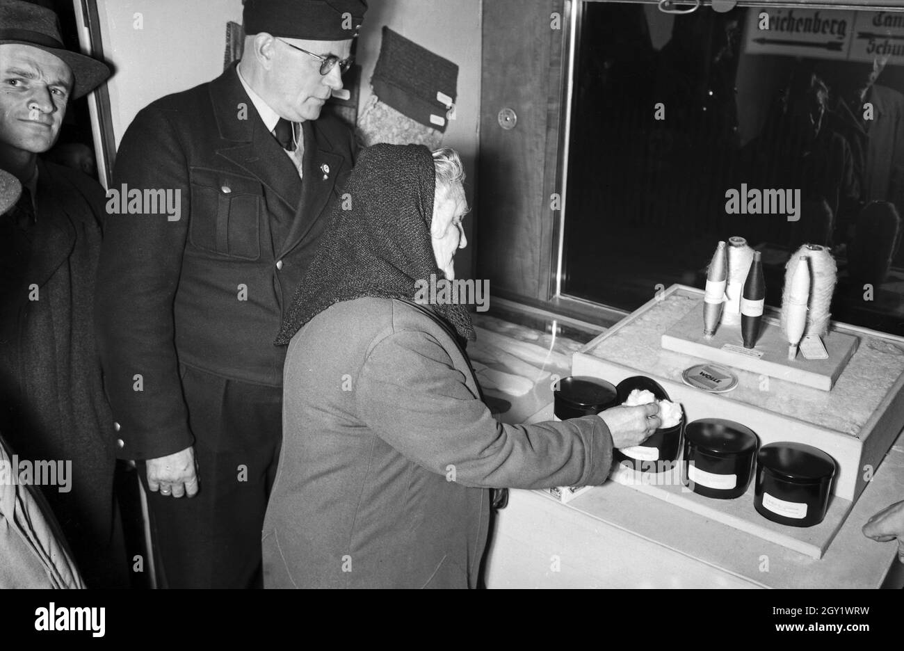 Ausstellungsbesucher informieren sich über die 'Sudetenfahrt der deutschen Technik' über die neuesten deutschen Erfahrungen auf dem Gebiet der Technik, hier bei verschiedenen Wollstoffen, Deutschland 1930er Jahre. Besucher, die durch die Ausstellung der Propagandaausstellung "Sonderfahrt der deutschen Technik", hier mit künstlichem Hocker, Deutschland 1930er Jahre, wandern. Stockfoto