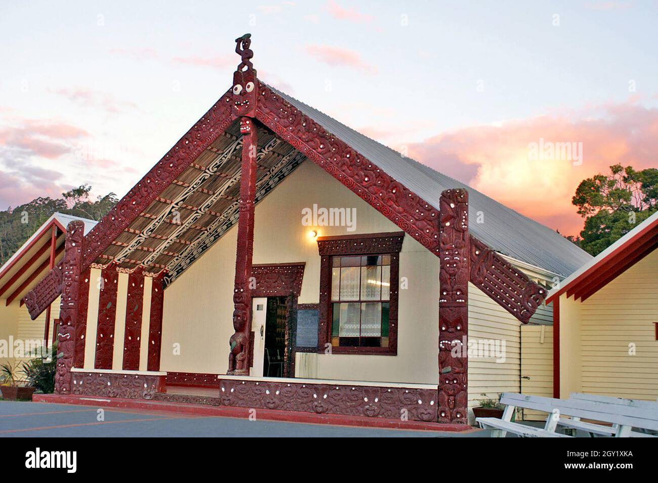 Ein traditionelles Maori Whare, oder Meeting House, in Rotorua, Neuseeland. Die Holzschnitzereien an der Außenseite des Versammlungshauses sind reich an Symbolik. Das Versammlungshaus ist ein Ort, an dem der Stamm und die Individuen gehört werden können, bekannt als tūrangawaewae. Die kulturelle Bedeutung des Versammlungsgebäudes an der Marae spiegelt sich in den Veranstaltungen wider, die dort stattfinden und von Gemeindeversammlungen bis hin zu Beerdigungen reichen. Stockfoto