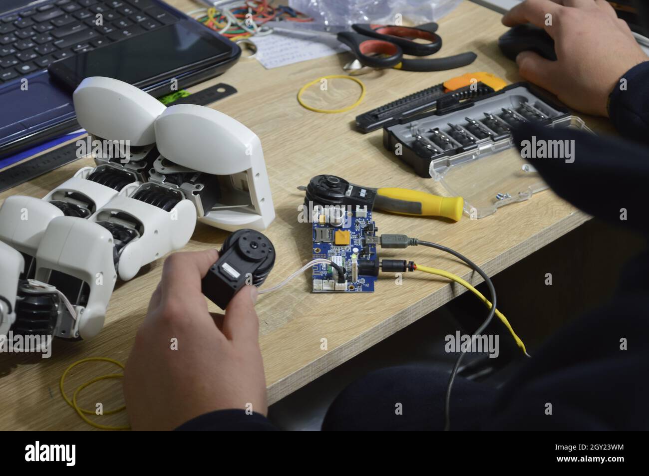 Mann repariert einen Roboter. Nahaufnahme von männlichen Händen, die einen zerbrochenen kleinen Roboter fixieren Stockfoto