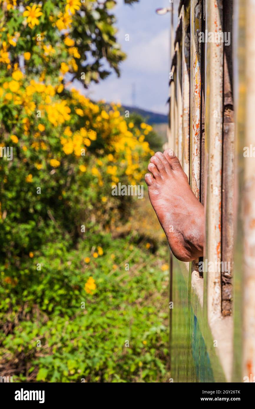 In Myanmar ragt ein menschlicher Fuß aus einem Zugfenster Stockfoto