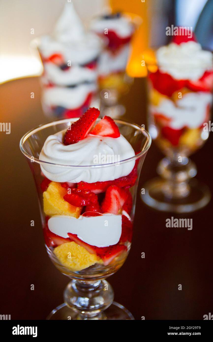 Gemischter Obstparfait in einem klaren transparenten Glas mit bunten Schichten und mit Erdbeeren gekrönt Stockfoto